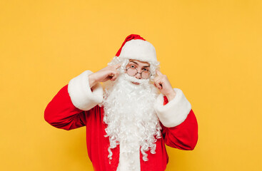 A serious Santa Claus points his fingers at his temple and looks at the camera with a serious face, showing a 