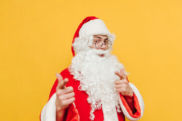 Happy Santa Claus shows his fingers to the camera and poses with a smile on his face. Christmas and New Year concept.
