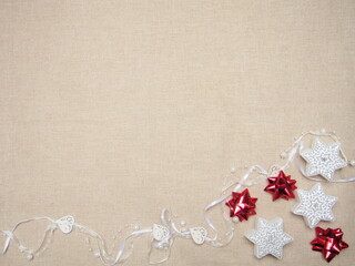 winter background with three star-shaped candles, a white ribbon with wooden carved hearts and red stars made of ribbons