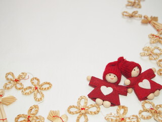 winter background with two red elves with a knitted hat and straw ornaments in the shape of angels and flowers, still life