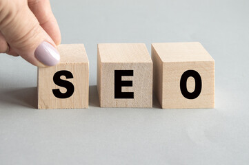 Wooden cubes with the word SEO and black letters, gray background, search engine optimization...