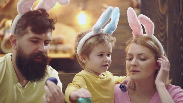 Happy easter family wearing bunny ears. Mother, father and son child paint and decorate eggs for holiday. Funny faces.