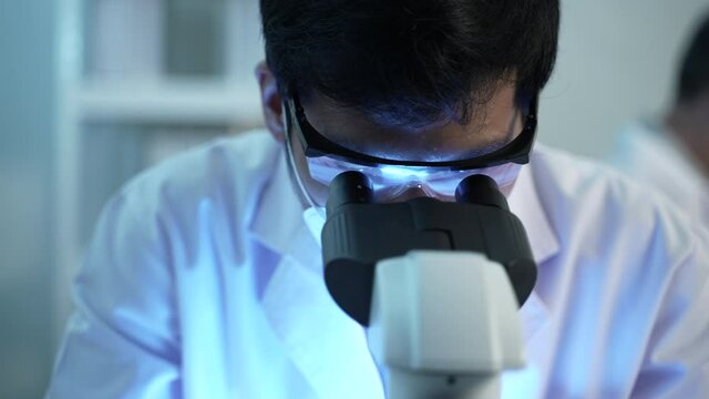 Asian scientist working with microscope in the laboratory, 