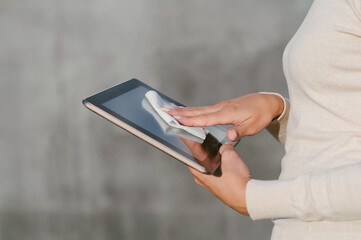 Girl disinfects wiping with a napkin, tablet. Against the background of a gray concrete wall.