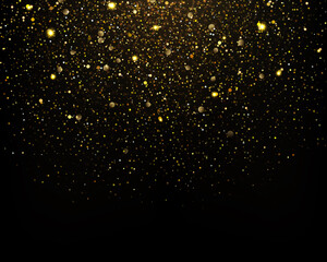 Gold glitter particles sparkles on black background.
