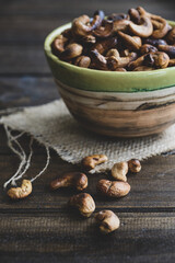 Ceramic bowl with roasted cashew nuts on a wooden table. Close up.