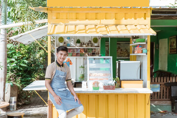 proud young asian man small business owner at his shop made of truck container selling street food