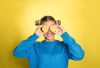 Girl holding lemon, on yellow background with copy space, smiling