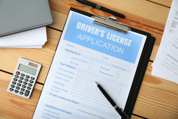 Driver's license application form, calculator and stationery on wooden table, flat lay