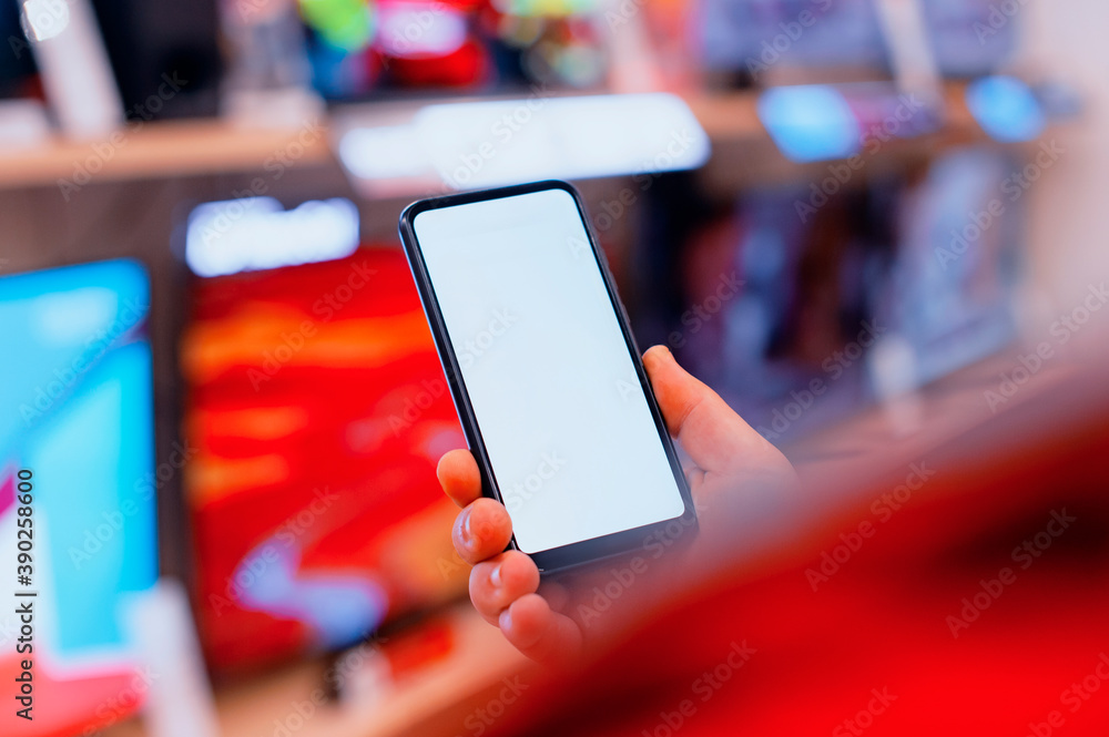 Poster mock-up of a smartphone with a white screen in the hands of a man. phone on the background of tvs in