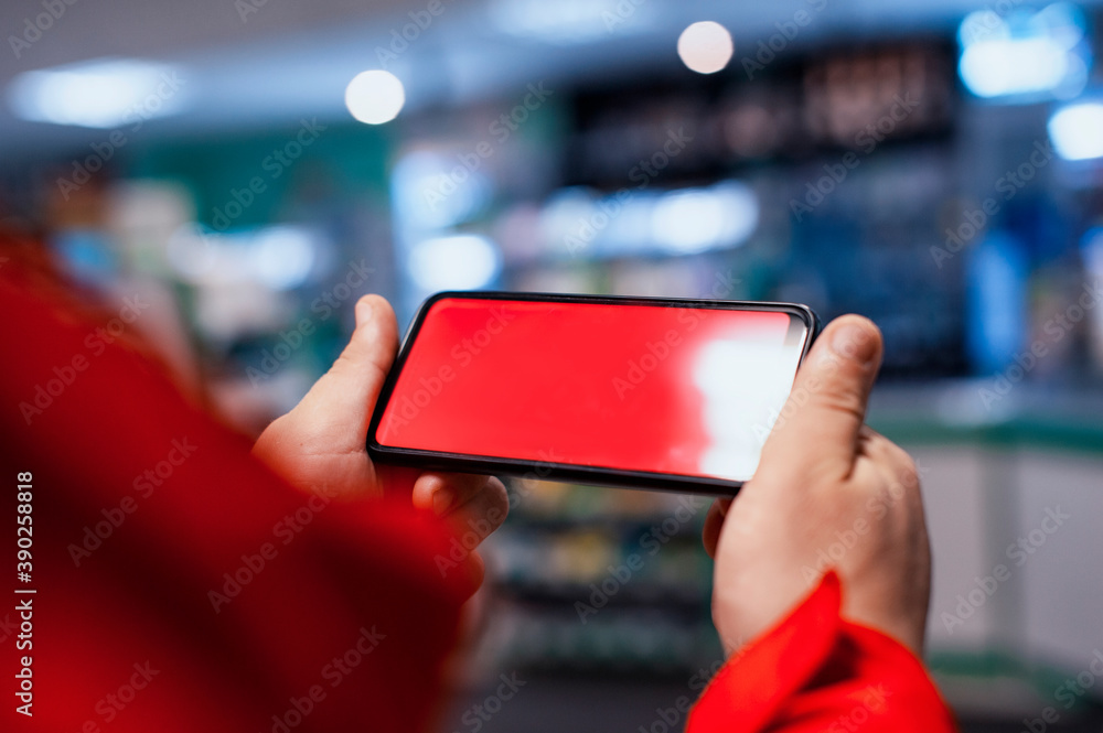 Poster mock-up of a smartphone with a red screen in the hands of a man. phone on the background of showcase