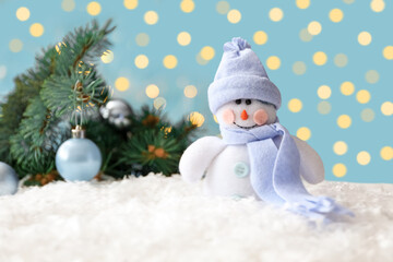 Snowman toy on snow against blurred festive lights. Christmas decoration