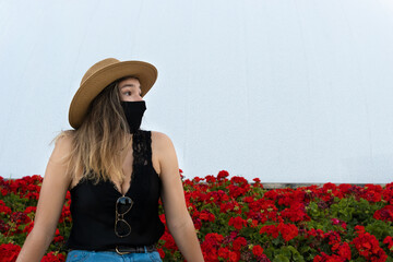 Closeup shot of a stylish girl with sunglasses and a hat, wearing a sanitary mask-the new normal