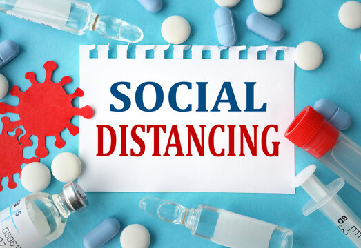 SOCIAL DISTANCING, text on white notepad paper against blue background. Social distancing concept to contain corona virus outbreak - health and medicine concept image