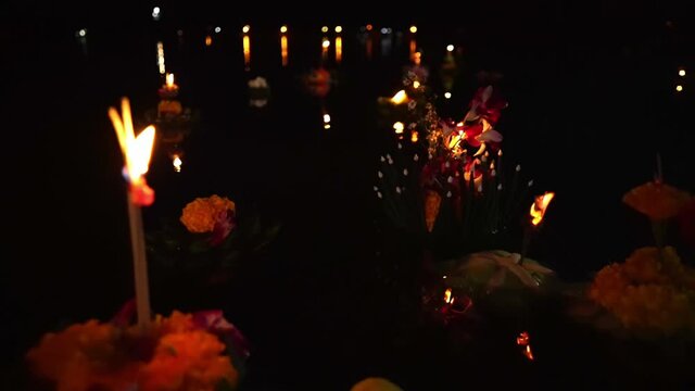 Dozens of beautifully decorated baskets called krathongs, float on the surface a lake at night with lit candles during the Loy Krathong Festival in Thailand.