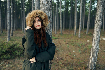 Fototapeta na wymiar Woman warm jacket with a hood near the trees on the background of the forest fresh air