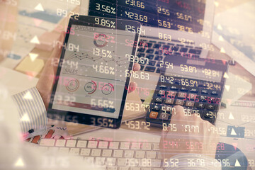 Double exposure of man's hands holding and using a digital device and forex graph drawing. Financial market concept.