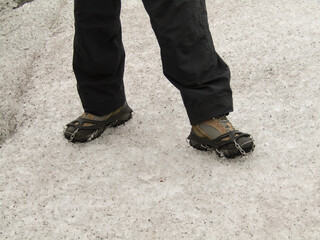 Women's feet with hiking shoes and crampon for traction, walking on Alaska glacier.