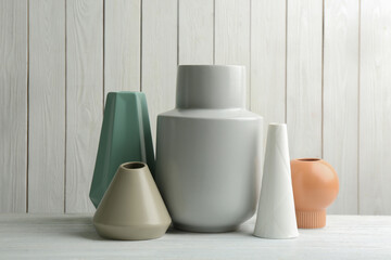Stylish ceramic vases on white wooden table