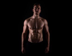 Fototapeta na wymiar Muscular male torso of fit bodybuilder on black background