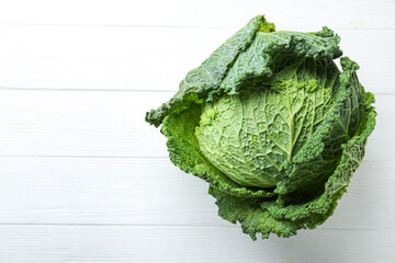 Fresh ripe savoy cabbage on white wooden table, top view. Space for text