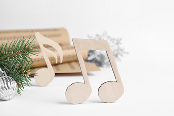 Wooden music note and fir tree branch with Christmas ball on white background