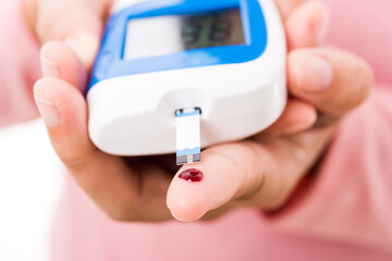 Closeup hands woman measur glucose test level check with blood on finger by glucometer she monitor and control high blood sugar diabetes and glycemic health care concept isolated on white background