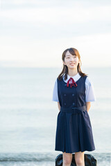海を背景に、笑顔を見せる女子高生