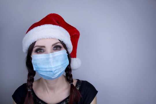 Woman wearing protection face mask against coronavirus. Woman in a mask and Christmas hat. Funny Christmas accessory. Medical mask, Medical gloves, Close up shot, Select focus, Prevention from covid19