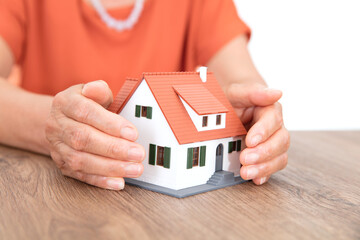 Closeup shot of old man's hands pampering small house model on table