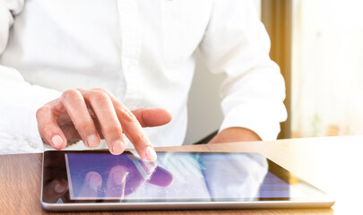 Close-up of hands navigating on a cell phone screen with an unfocused computer in the background in...