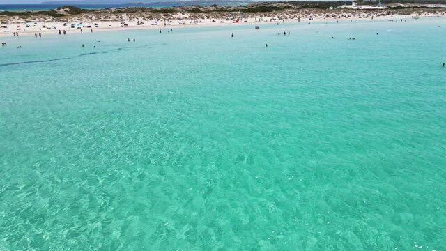 Incredibly beautiful beach on the Formentera island. Many unrecognizable people are relaxing on the beach on the island