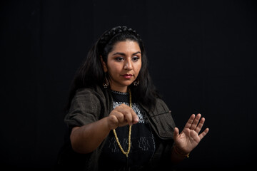
Mujer latina con cabello negro ojos expresivos y sonriente con hermosa sonrisa, sobre fondo negro, viste ropa étnica y mantón negro, sanadora y sanadora mexicana
