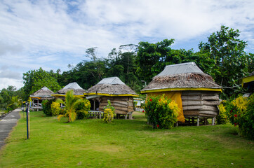 Small huts surrounded by greenery under a cloudy sky in Manase, Samoa