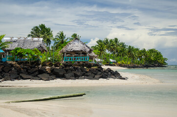 Beach surrounded by palm trees, small cottages, and the sea in the Savai'i island, Samoa