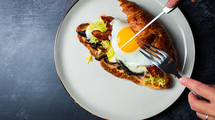 Cutting Portobello Croissant Breakfast Sandwich with sunny up egg