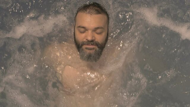 Man with closed eyes relaxing in hot tub, top view