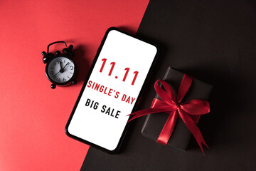 11:11 sale shopping concept, Top view of gift box wrapped in black paper and bow ribbon and mobile...