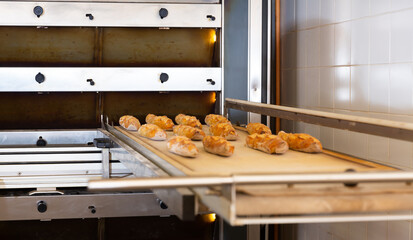 Freshly baked baguettes on worktable near oven in bakery workshop. Traditional baking process