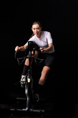 Smiling fitness girl racing on indoor exercise bike, front facing shot
