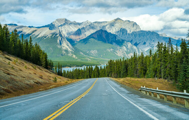 Rural road in the forest with mountains in the background. Alberta Highway 11 (David Thompson Hwy) along the Abraham lake shore. Jasper National Park, Canada.