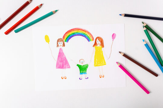 Child's drawing by colored pencils of LGBT family. Top view. Two mothers and their son. Rainbow. Colored pencils on white table.