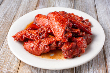 A view of a plate of Chinese style hot wings, in a restaurant or kitchen setting.