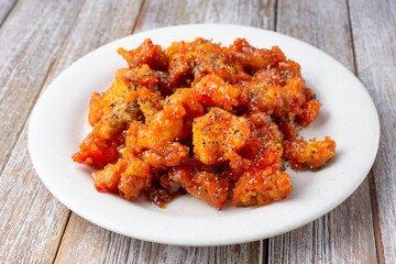 A view of a plate of black pepper chicken, in a restaurant or kitchen setting.