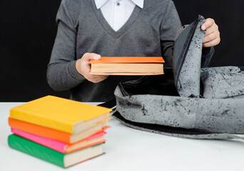 Closeup young boy packing backpack with books for the school