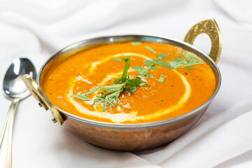 A view of a bowl of chicken tikka masala, in a restaurant or kitchen setting.