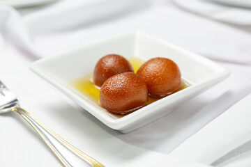 A view of a sauce of gulab jamun, in a restaurant or kitchen setting.