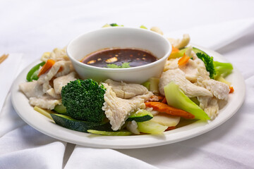 A view of a plate of chicken and steamed veggies, in a restaurant or kitchen setting.