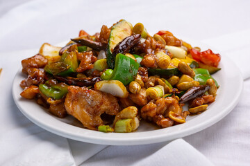 A view of a plate of kung pao chicken, in a restaurant or kitchen setting.