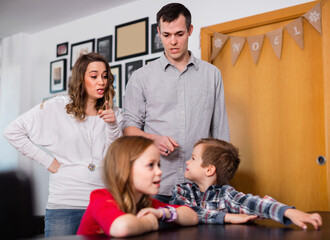 Young angry parents lecturing their children for bad behavior at home